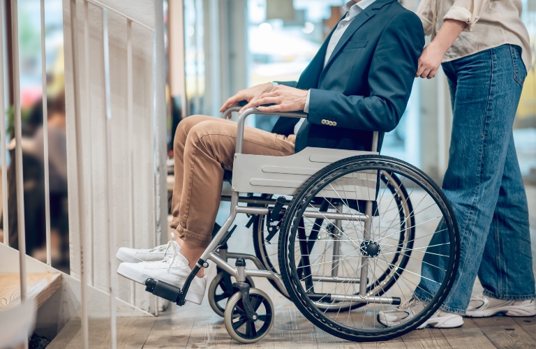 Man in wheelchair and accompanying assistant