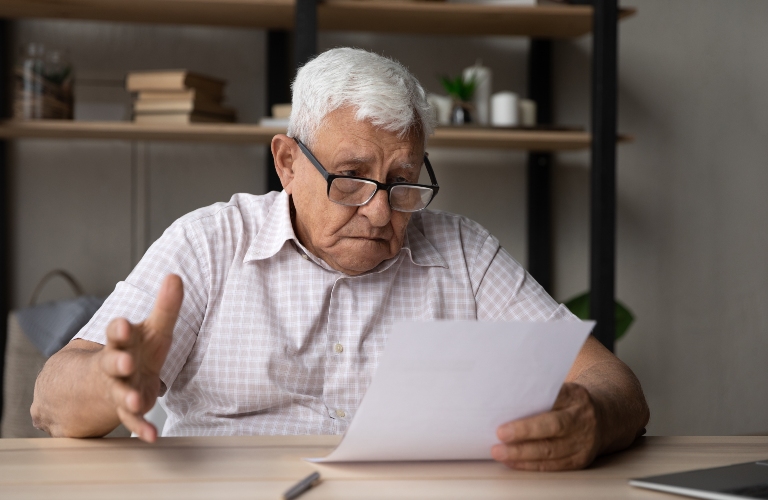 Confused frustrated elder senior 80s man in glasses reading document